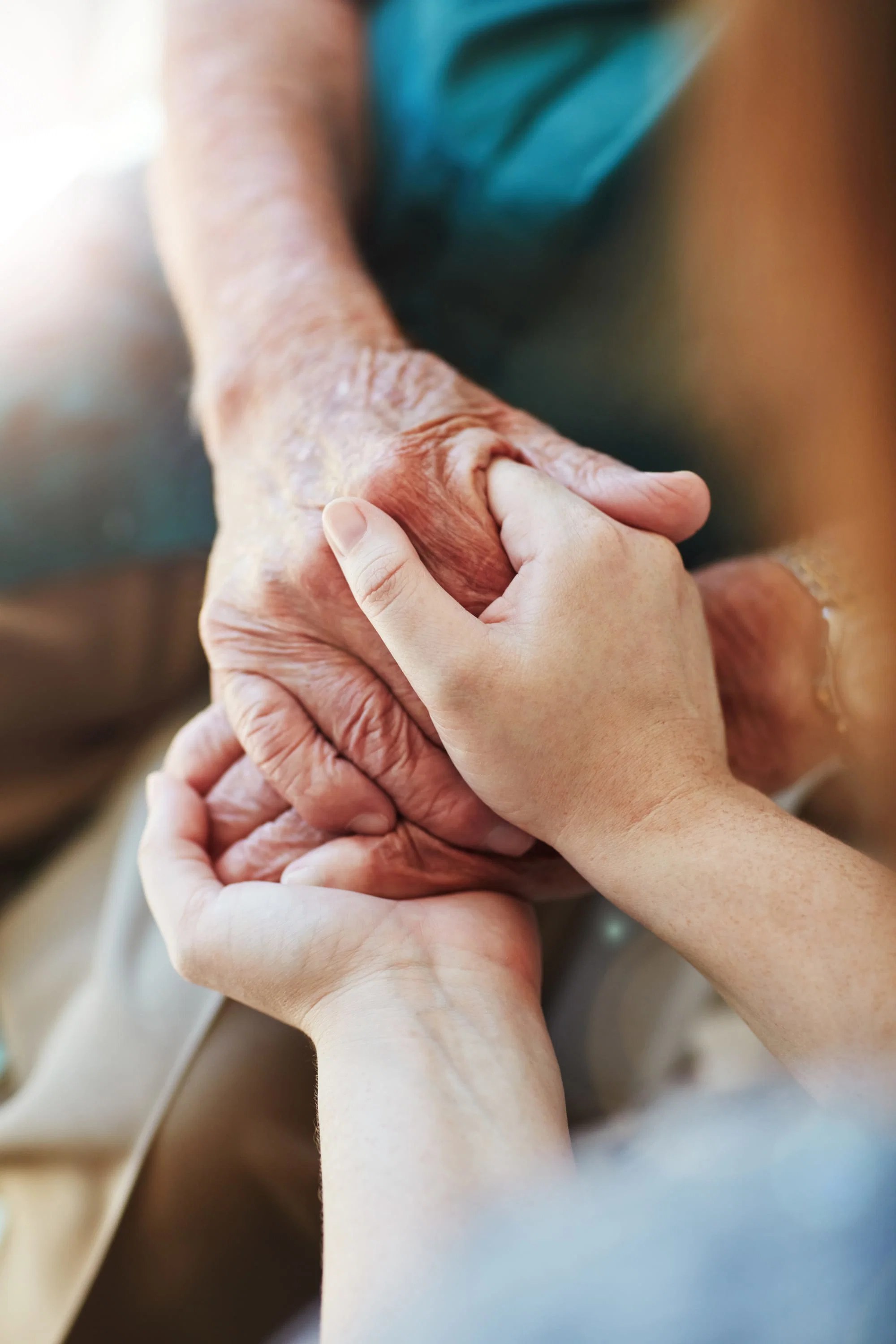 Caregiver warmly holding hands with a senior at home
